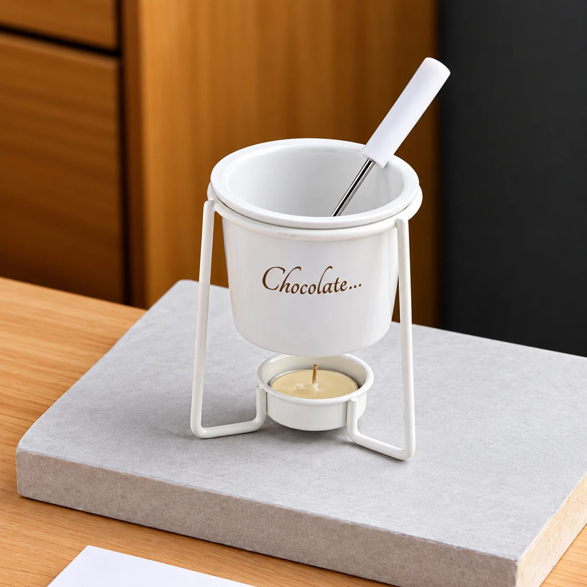 White ceramic chocolate fondue bowl on a metal stand with tealight and dipping fork